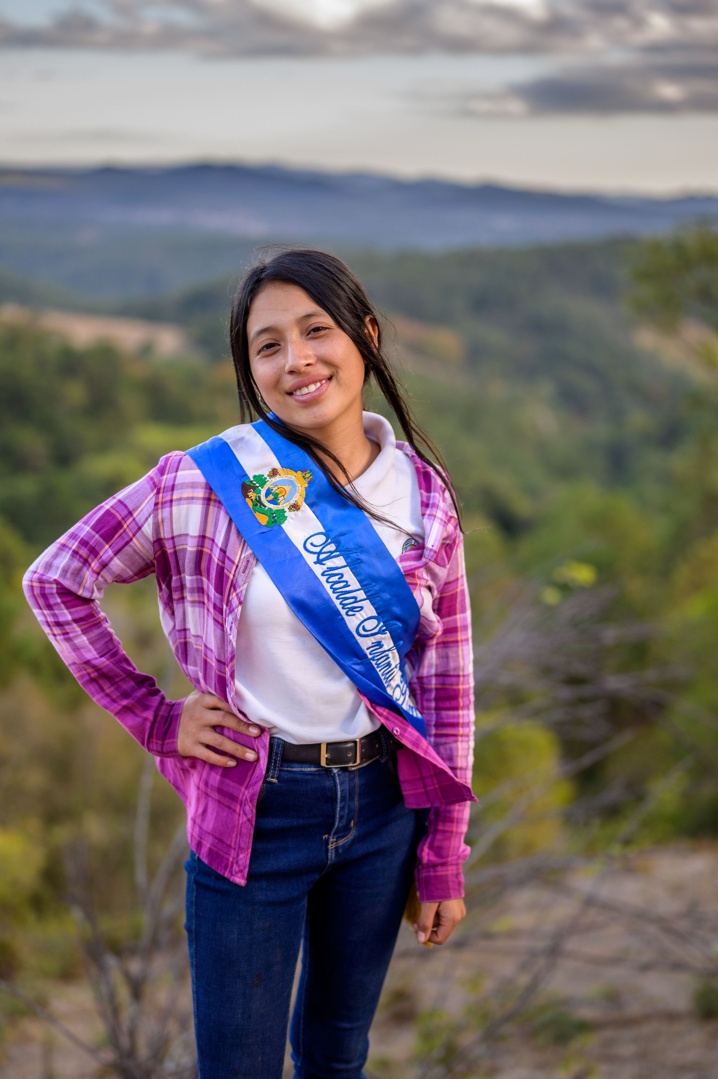 Ni&ntilde;a hondure&ntilde;a con una faja azul mientras sonr&iacute;e y mira a la c&aacute;mara