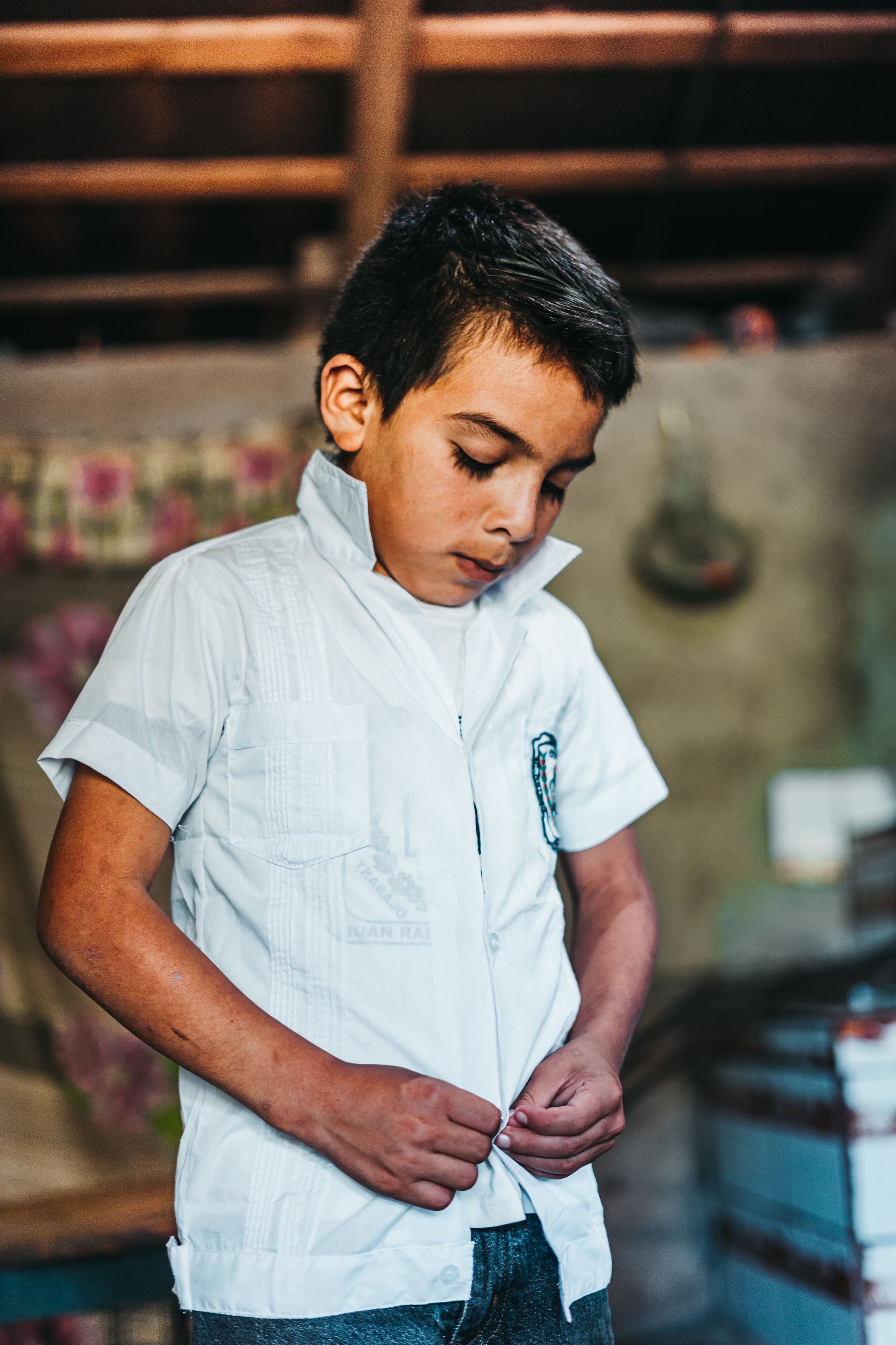 Ni&ntilde;o hondure&ntilde;o con camisa de cuello blanco, mir&aacute;ndose las manos.